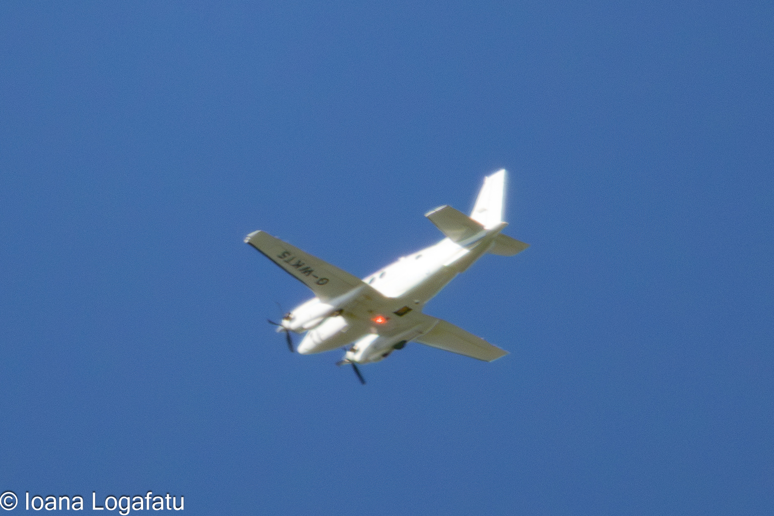 Small aircraft soars high against a clear sky